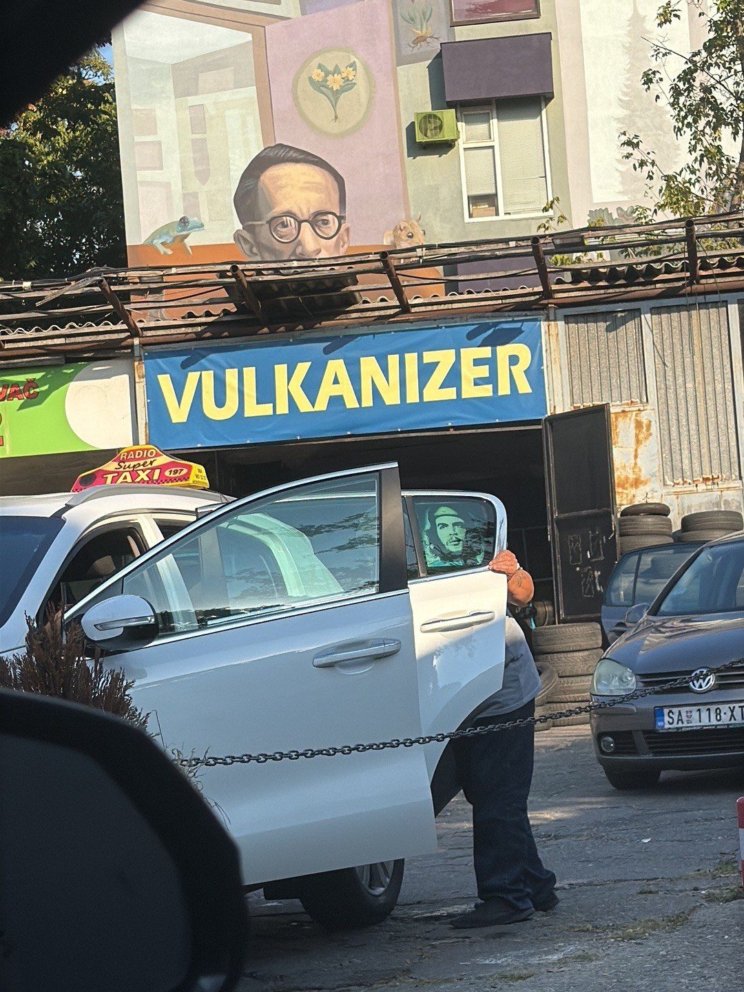 Majstor menja gumu na automobilu ispred radionice